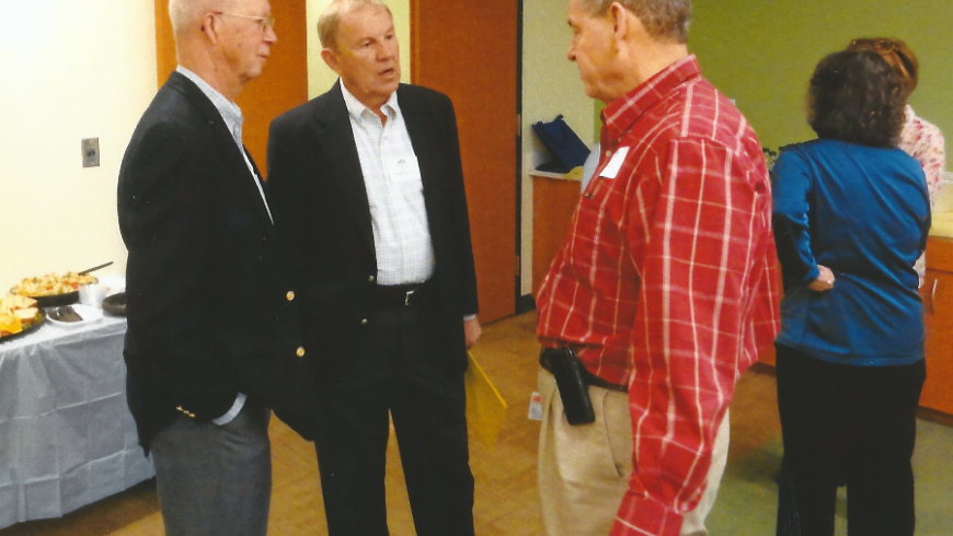 Three men have a conversation. 