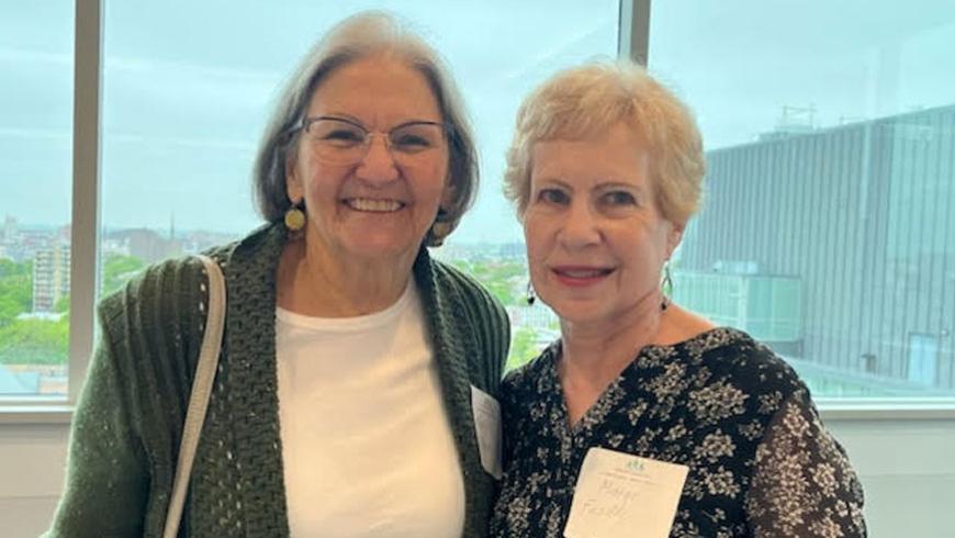 Two women stand next to each other and smile.