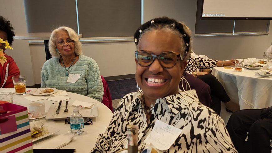 A woman smiles while sitting at a table.