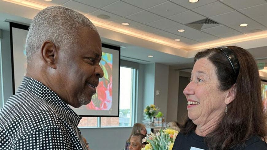 A man and a woman smile while having a conversation.