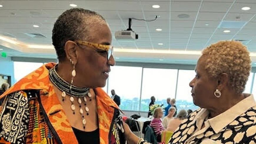Two women have a conversation while standing.