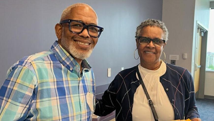 A man and a woman stand next to each other and smile.
