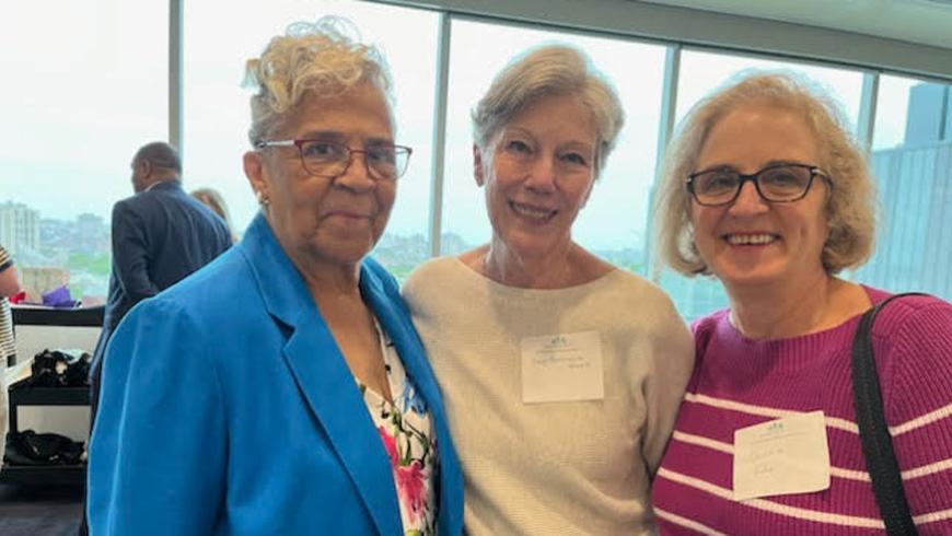 Three women stand next to each other and smile.
