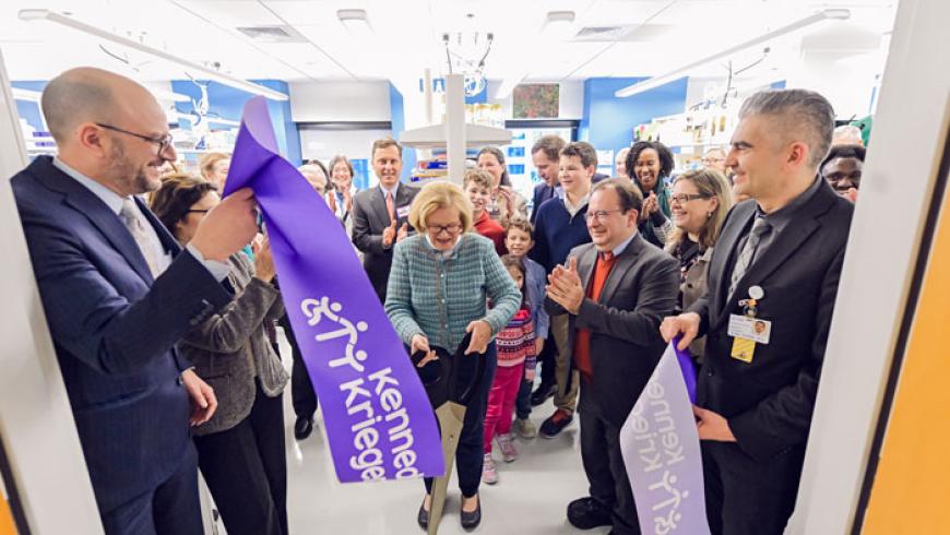 Sally Johnston cuts the ribbon on the Johnston lab. A large group of people are standing behind her applauding.