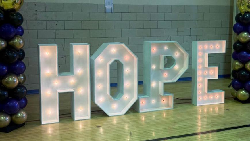The word Hope spelled out in lighted letters sits between columns of balloons at the 20th anniversary prom.