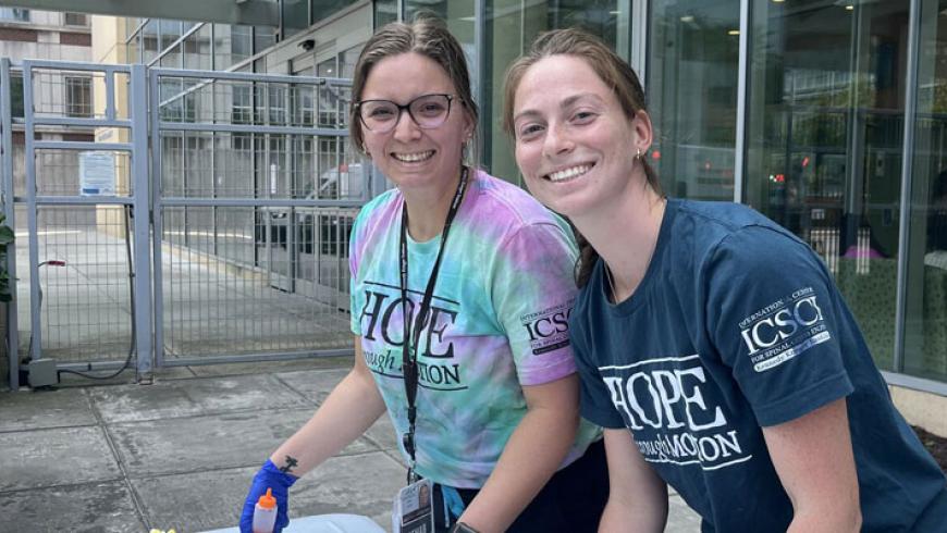 Two ICSCI staff members paint t-shirts as part of a 20th anniversary event.