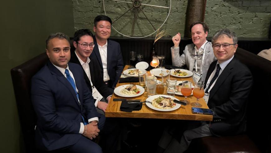 Five people sitting in a booth during an AES Conference group dinner.