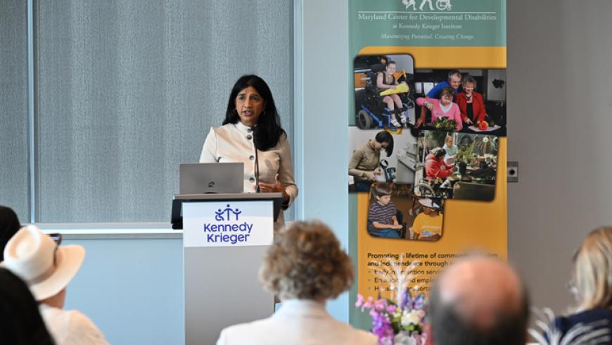 Lt. Governor Aruna Miller speaks at the podium during the conference, with an MCDD banner over her left shoulder.