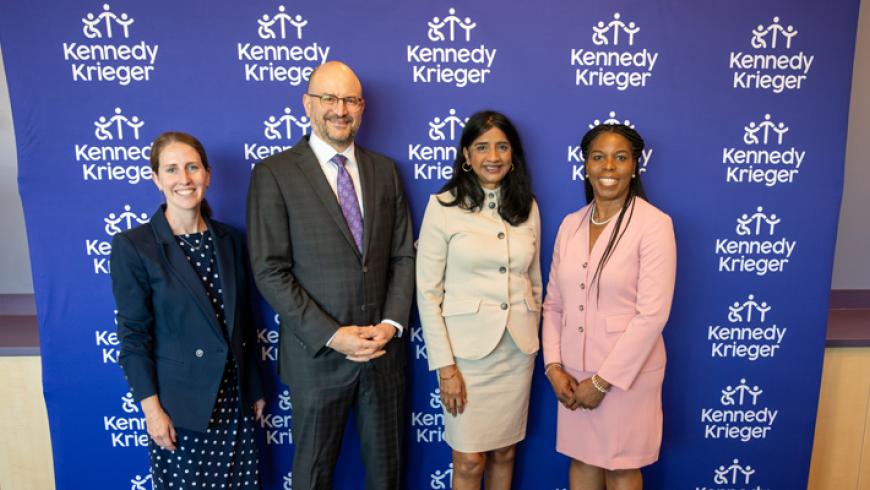 Kennedy Krieger AVP of government relations Emily Arneson, Kennedy Krieger president and CEO Dr. Brad Schlaggar, Maryland Lt. Governor Aruna Miller, and Dr. Mirian Ofenodu smile while standing in front of a Kennedy Krieger step and repeat banner.