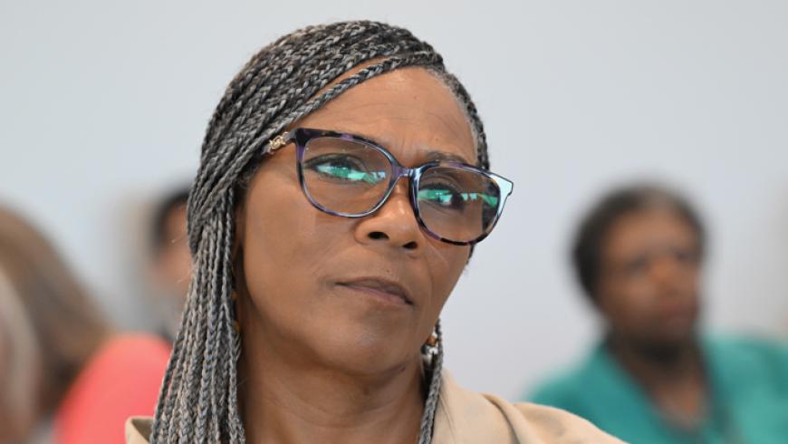 A closeup of a woman listening to a conference presentation.