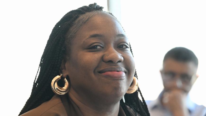 A woman smiles while sitting among other conference attendees.