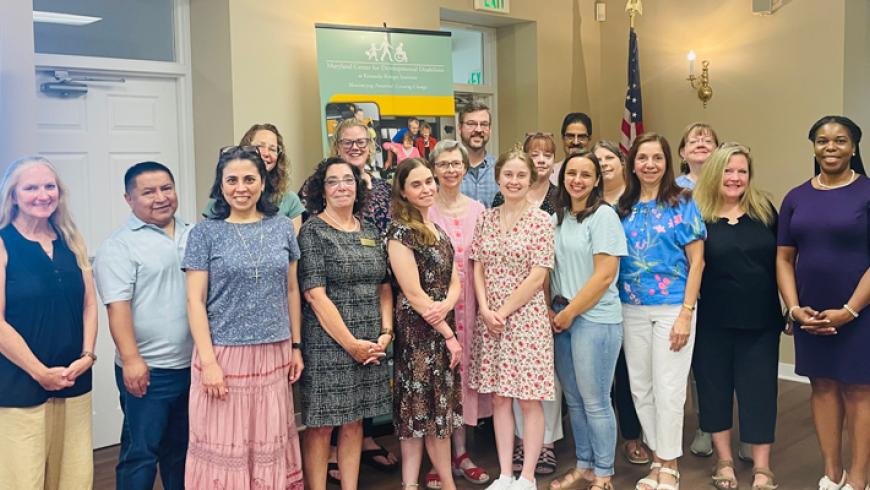 A large group of faith inclusion ambassadors smile in a group photo in a coference room.